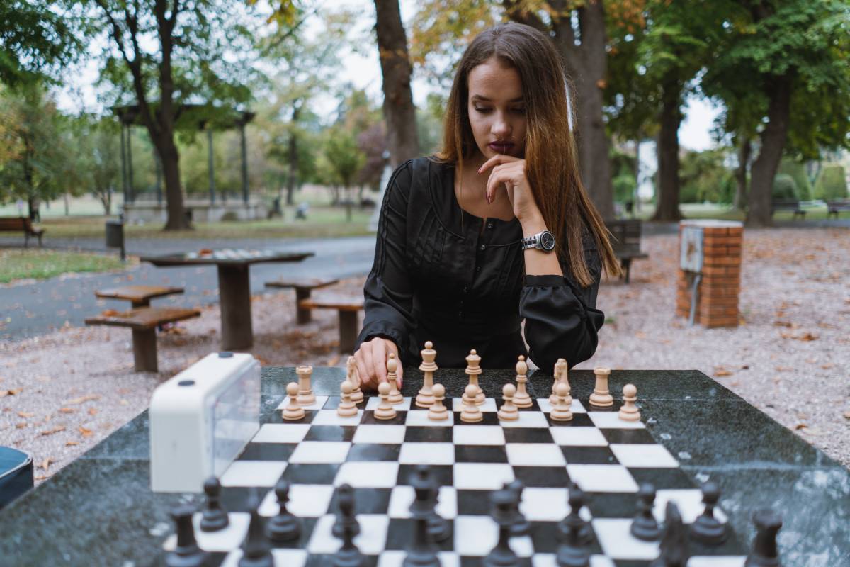 une femme joue aux échecs dans un parc